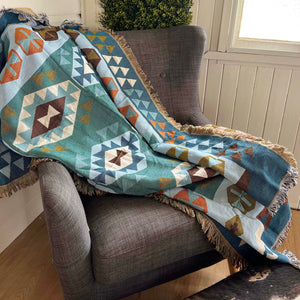 This lovely throw-blanket features; Southwest pattern, beautiful blue hues and fringed edge. Fully reversible pink accent so you can change your seasonal style.  Perfectly sized for napping, reading or simply admiring. Can be worn as an shawl as seen in stylish cowgirl magazines.   Interior gorgeousness!! A throw is more than a throw. Their versatility can be used to warm up a room, add glamour, colour and texture or simply provide the finishing touch to any space