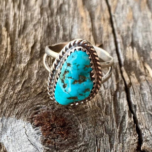 Get your hands on this stunning Vintage Ring. It’s has an exquisite Turquoise stone, you won’t want to take your eyes of it.   This little fellow is an oldie but a goodie. Navajo made this ring has been set with a Kingman nugget turquoise in a very traditional style. Set with a sterling saw tooth bezel and accented with sterling twist rope. Vintage pre 2000. Stamped. Size of Setting: 5/8” by 1/2”