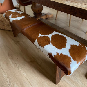 Give your living space a dose of natural beauty with this cowhide bench seat.  Perfect as a pair on either side of the dining table, place one at the end of the bed or at the entrance when putting your boots on. We do pick the nicest hides for their desired pattern and colour.  Made at Swan Creek; we handcraft these 5ft bench seats from native woods; finished with smoked-amber stain. Then custom upholster with cowhide and accent with trim of Mex nail-heads. (Cowhide cushion top with foam inner) 