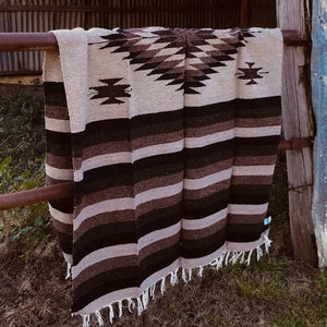 These versatile Southwest blankets are perfect to spice up your living space.  Lay it over the bed or patio furniture, use as an accent floor rug, wall tapestry or take it on your weekend adventure.    Made in Mexico; hand-loomed falsa blanket with diamond centre. Fringe ends. Washable Recycled Cotton & Acrylic blend. Measures: generous 79"X50" (inches). Medium weight, they make a nice bed topper.