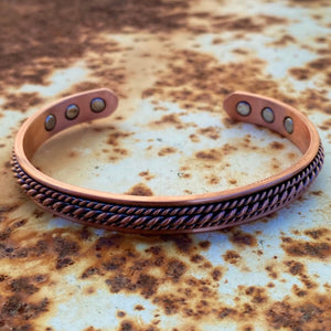 Slimmer than the cowboys cuff, however still a nicely weighted solid copper.   Vintage finish ~ matches with the Western Scroll ring.  Western style embossed with 6 magnetic inlays (considered for holistic health benefits). Copper jewellery has been worn since ancient time. It is thought to help ease aches + pains and have numerous health benefits. It’s is also an excellent western accessory.