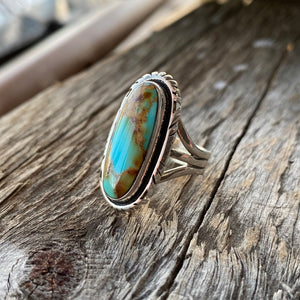 Get your hands on this stunning Navajo Ring. It’s has an exquisite Turquoise stone, you won’t want to take your eyes of it.   Made by Navajo artist Alfred Joe, this ring is set in Sterling silver with stunning Pilot Mountain turquoise. The oval cut stone is set in a smooth sterling bezel and accented with a cut and notched edge. Stamped. Size of Setting: 1 1/8 ” by 1/2 ”.  Heirloom item. One of a kind collectors item to be worn, admired and treasured.