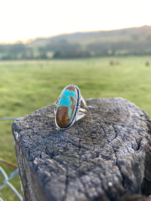 Get your hands on this stunning Navajo Ring. It’s has an exquisite Turquoise stone, you won’t want to take your eyes of it.   Made by Navajo artist Alfred Joe, this ring is set in Sterling silver with stunning Pilot Mountain turquoise. The oval cut stone is set in a smooth sterling bezel and accented with a cut and notched edge. Stamped. Size of Setting: 1” by 1/2 ”