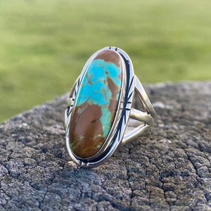 Get your hands on this stunning Navajo Ring. It’s has an exquisite Turquoise stone, you won’t want to take your eyes of it.   Made by Navajo artist Alfred Joe, this ring is set in Sterling silver with stunning Pilot Mountain turquoise. The oval cut stone is set in a smooth sterling bezel and accented with a cut and notched edge. Stamped. Size of Setting: 1” by 1/2 ”