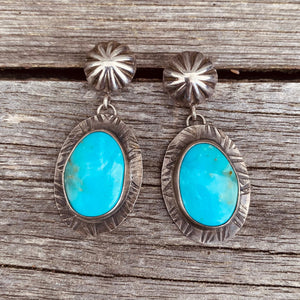 Natural Birds Eye turquoise from a small Turquoise Mountain mine in Nevada. Bright blue stones with a pop of teal green and black matrix. Stones measure 28x16mm.   Hand-formed ‘post studs’ with fletcher pendant setting. These earrings hang lovely at 1.75". 