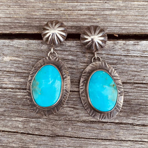 Natural Birds Eye turquoise from a small Turquoise Mountain mine in Nevada. Bright blue stones with a pop of teal green and black matrix. Stones measure 28x16mm.   Hand-formed ‘post studs’ with fletcher pendant setting. These earrings hang lovely at 1.75". 