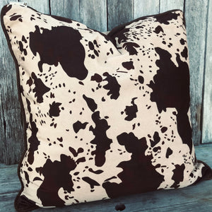 The reversible Caldwell euro sham features faux cowhide print fabric with an embellished tan suede reverse. Leather and stylish Conchos provide a touch of western flare. This is stunning piece coordinates with many of our lodge and western collections.  Measures 27" x 27" Grande Euro cushion with inner. Hidden zipper closure.  Sourced from Texas USA. As seen styled in Western Magazines.  We pack em tight to keep the delivery cost down.
